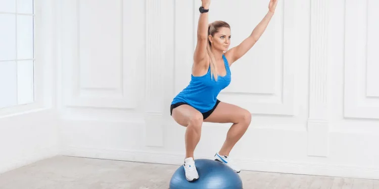 donna a casa su un bosu in posizione di squat cercando di tenere equilibrio