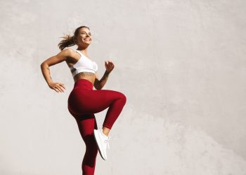 una donna con top bianco e leggings rossi fa esercizio