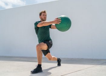 Uomo in allenamento outdoor esegue un affondo laterale con la palla medica