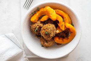 Iscriviti subito alla dieta Melarossa e scarica l'app 10 In primo piano su un piatto fondo bianco ci sono delle polpette di zucca croccanti e della zucca cotta al forno.