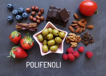su sfondo grigio scuro una collezione di alimenti ricchi di polifenoli: mirtilli, cioccolato, pomodori, fragole, olive verdi, mandorle, noci e lamponi