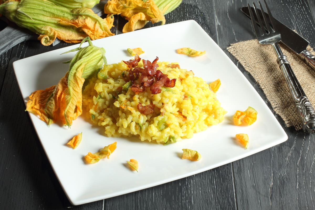 Risotto: le migliori ricette sane e golose 18 in primo piano un piatto di risotto con fiori di zucca decorato con del guanciale croccante