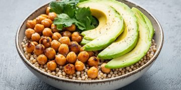 su tavolo nero, ciotola con sorgo, avocado e ceci