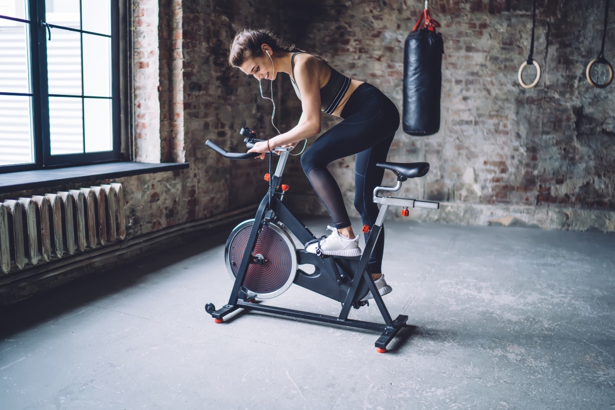 donna a casa vestita da fitness sta facendo allenamento spinning sulla spin bike