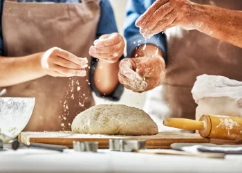 le mani di un uomo e una donna che preparano il pane in casa