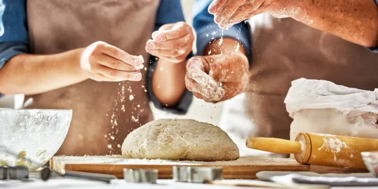 le mani di un uomo e una donna che preparano il pane in casa