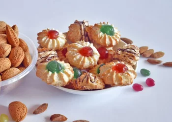 su tavolo bianco, 1 piatto con mandorle e un altro piatto bianco con pasta di mandorle, vicino