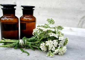 su tavolo di marmo bianco, un mazzo di Achillea millenium e 2 bottiglie maroni di olio essenziale