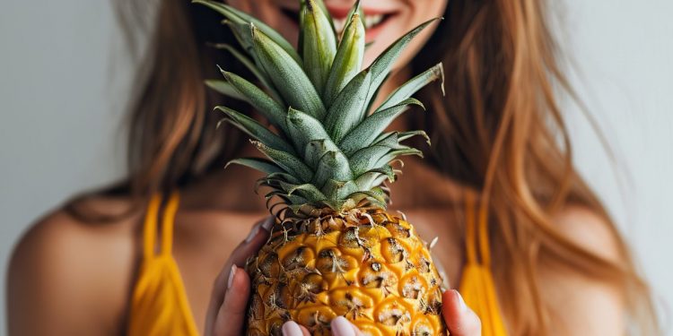 donna con costume da bagno prende in mano un ananas