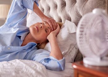 donna nel letto che ha vampate di calore in menopausa