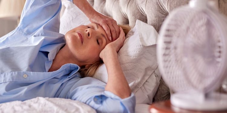 donna nel letto che ha vampate di calore in menopausa