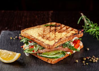 piano di lavoro nero per cucina, panino con pane tostato con avocado, rucola, fette di limone. come tostare il pane velocemente