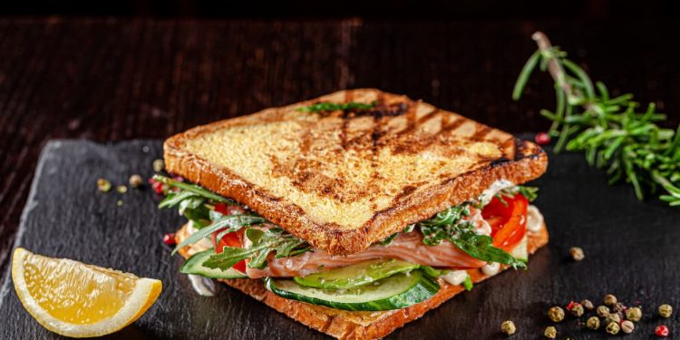 piano di lavoro nero per cucina, panino con pane tostato con avocado, rucola, fette di limone. come tostare il pane velocemente