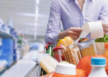 Una donna al supermercato che legge la sua lista della spesa