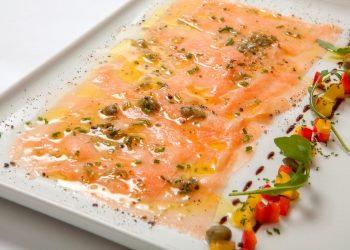 piatto rettangolare con carpaccio di salmone marinato decorato con capperi e verdure tagliate