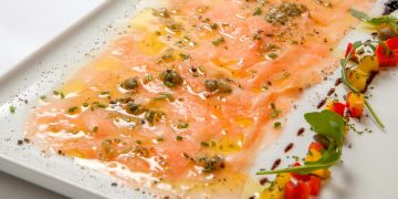 piatto rettangolare con carpaccio di salmone marinato decorato con capperi e verdure tagliate