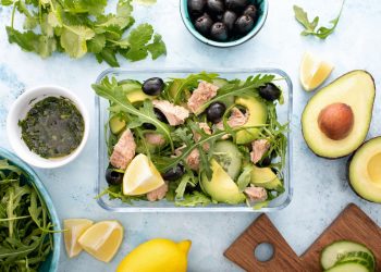 lunch box con insalata e tonno in scatola con attorno avocado, olive, limone