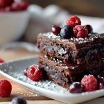 un piatto con una porzione di brownies e frutti di bosco