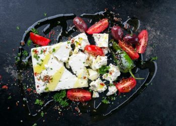 su sfondo nero, formaggio feta greca tagliata assieme con pomodori e peperoni