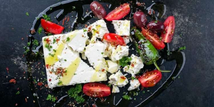 su sfondo nero, formaggio feta greca tagliata assieme con pomodori e peperoni