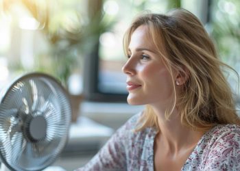 Donna in ufficio con il ventilatore perché sta combattendo conto sintomi menopausa