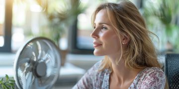 Donna in ufficio con il ventilatore perché sta combattendo conto sintomi menopausa