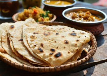 Un piatto di piadine vuote con accanto delle ciotole con alcuni cibi