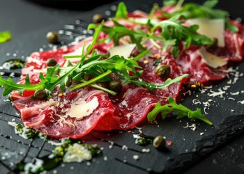 su tagliere di marmo nero primo piano di un carpaccio di manzo con rucola e Parmigiano