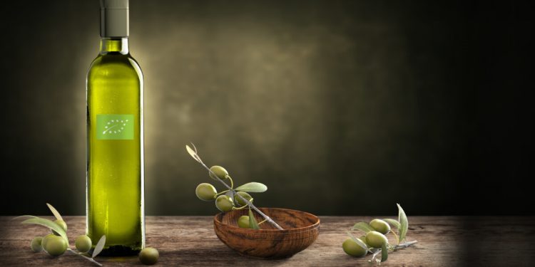 bottiglia di olio biologico con logo di Eccebio e olive verde su un tavolo di legno