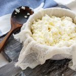 su tagliere di legno ciottola con fiocchi di latte fatto in casa e cucchiaio di legno