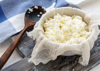 su tagliere di legno ciottola con fiocchi di latte fatto in casa e cucchiaio di legno