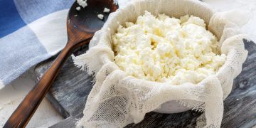 su tagliere di legno ciottola con fiocchi di latte fatto in casa e cucchiaio di legno