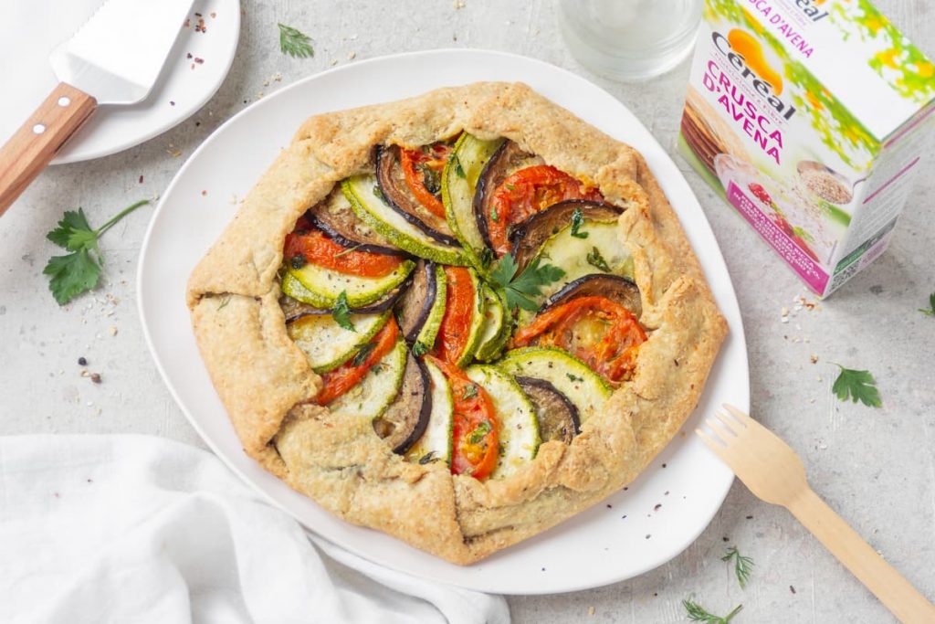 Torta salata con ratatouille: una ricetta gustosa e facile da preparare 4 Su sfondo bianco piatto bianco con torta salata con ratatouille e accanto la confezione delle crusca d'avena di Céréal