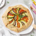 Su sfondo bianco piatto bianco con torta salata con ratatouille e accanto la confezione delle crusca d'avena di Céréal