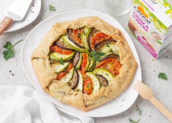 Su sfondo bianco piatto bianco con torta salata con ratatouille e accanto la confezione delle crusca d'avena di Céréal