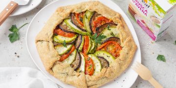 Su sfondo bianco piatto bianco con torta salata con ratatouille e accanto la confezione delle crusca d'avena di Céréal