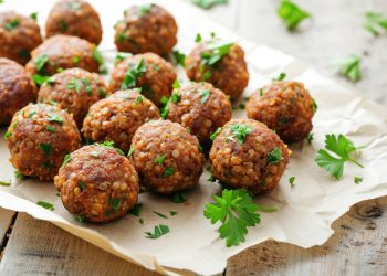 su tavolo primo piano di un vassoio con polpette di lenticchie e prezzemolo con sotto carta da forno