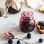 vasetto con marmellata e fetta biscottata ricoperta di marmellata di more, more sparse