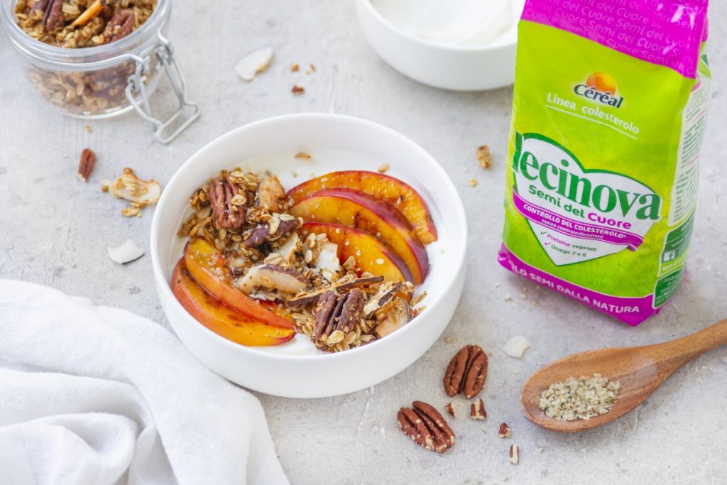 Su tavolo di marmo ciotola con una yogurt bowl, accanto i semi del cuore di Céreal, semi e frutta secca