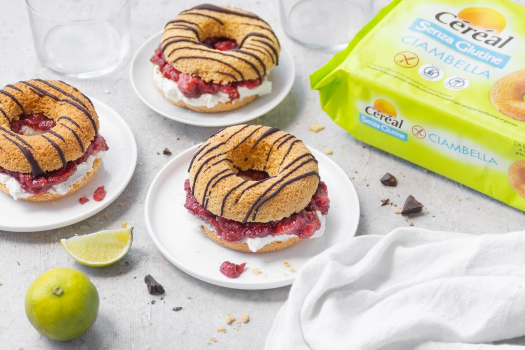 tre piattini bianchi con tre ciambelle sandwich, limone, e una confezione di ciambelle senza glutine Cereal
