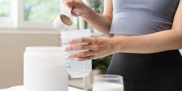 una donna che prepara un frullato con proteine in polvere