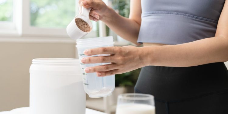 una donna che prepara un frullato con proteine in polvere