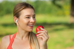 Iscriviti subito alla dieta Melarossa e scarica l'app 13 Bellissima donna con le cuffie che mangia una mela rossa dopo la corsa.