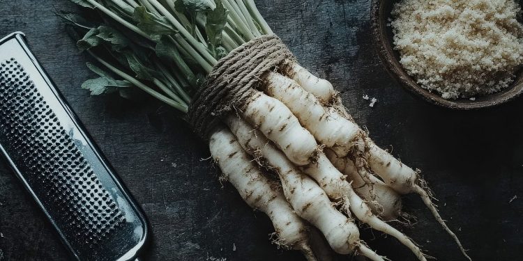 Immagine di un tavolo con della pastinaca e una grattugia