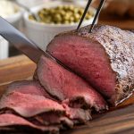 Roast beef all’inglese: ricetta, cottura, foto e video 1 In primo piano su un tagliere di legno viene tagliato sottile il roast beef all'inglese.