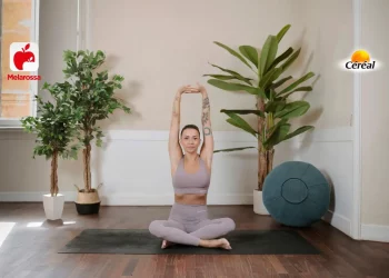 donna sul tappetino mentre esegue una posizione yoga, un pallone e tre piante