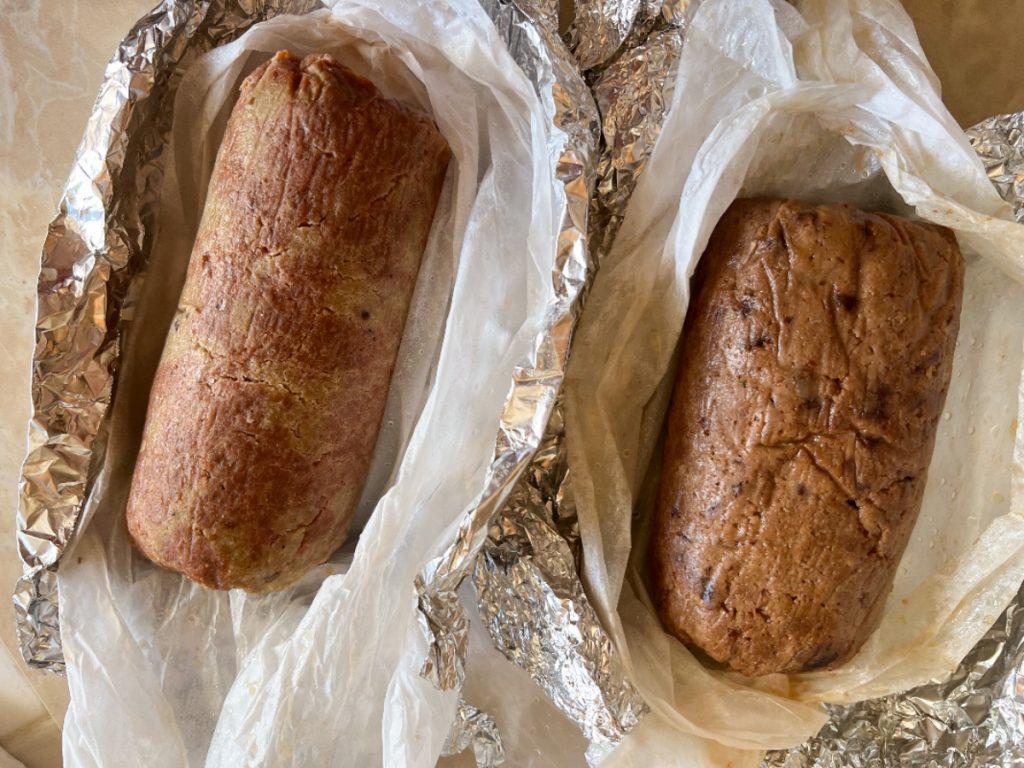 primo piano su un tavolo avvolto nella carta argentata un polpettone di ceci al forno, accanto u altro appena uscito dal forno