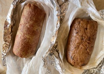 primo piano su un tavolo avvolto nella carta argentata un polpettone di ceci al forno, accanto u altro appena uscito dal forno