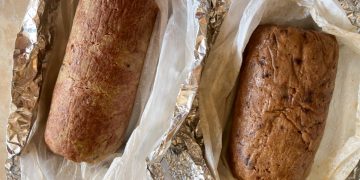primo piano su un tavolo avvolto nella carta argentata un polpettone di ceci al forno, accanto u altro appena uscito dal forno