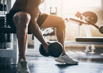 Uomo che solleva un peso in palestra, stimolando l'anabolismo muscolare attraverso l'allenamento di forza